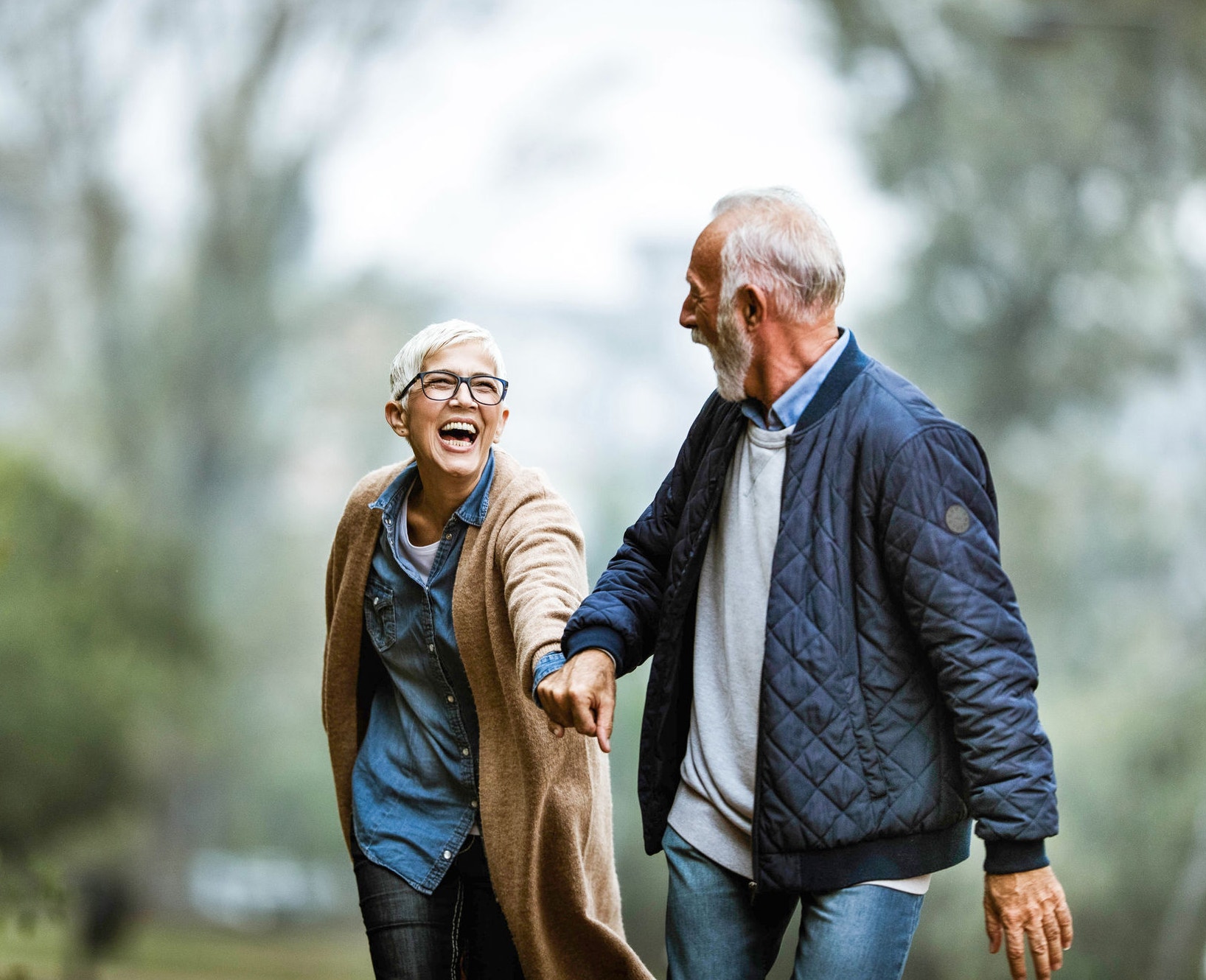 Cheerful senior couple having fun in the park. Focus is on woman. Copy space.