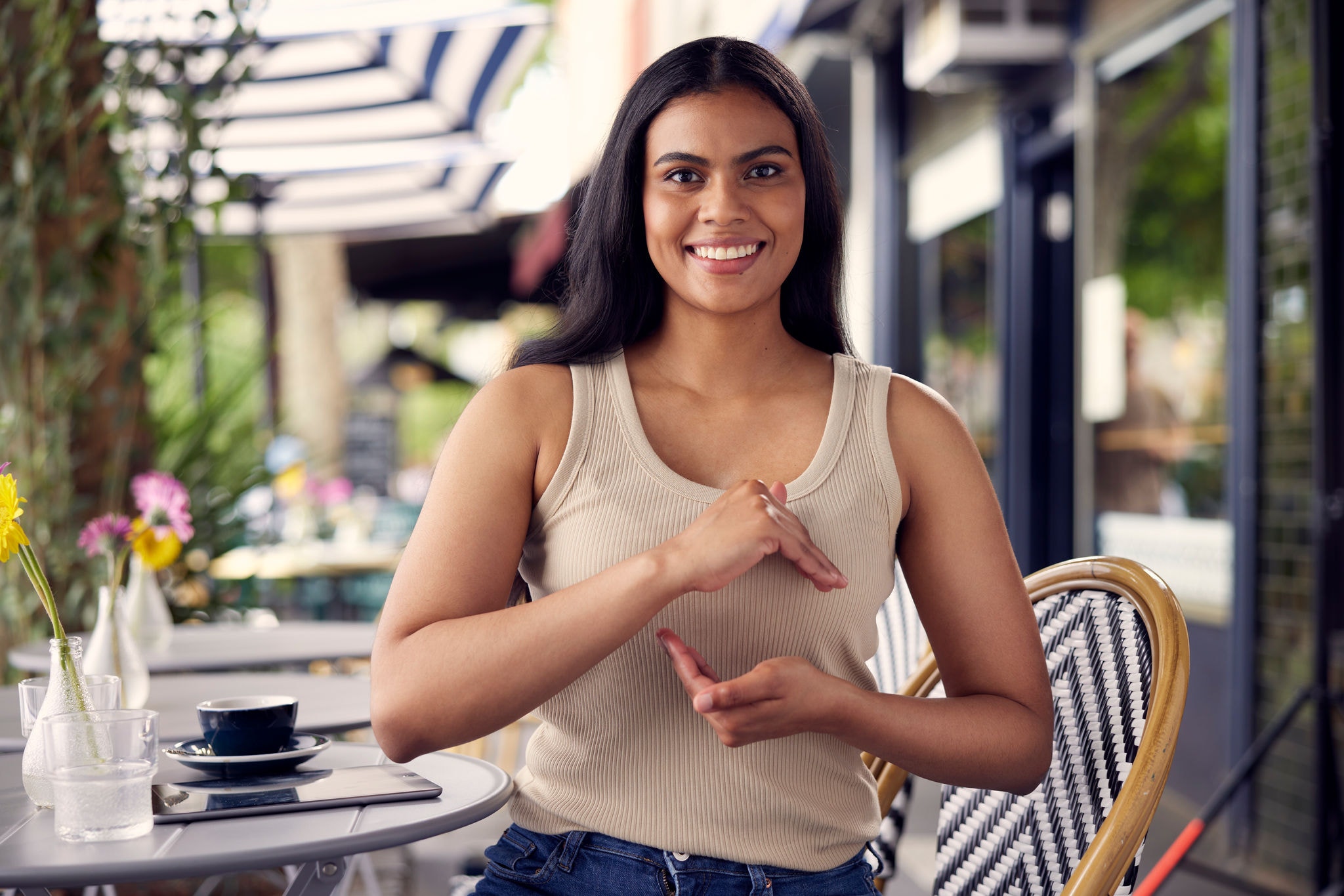 Young girl at a restaurant, looking at the camera while forming the industry fund logo with her hands