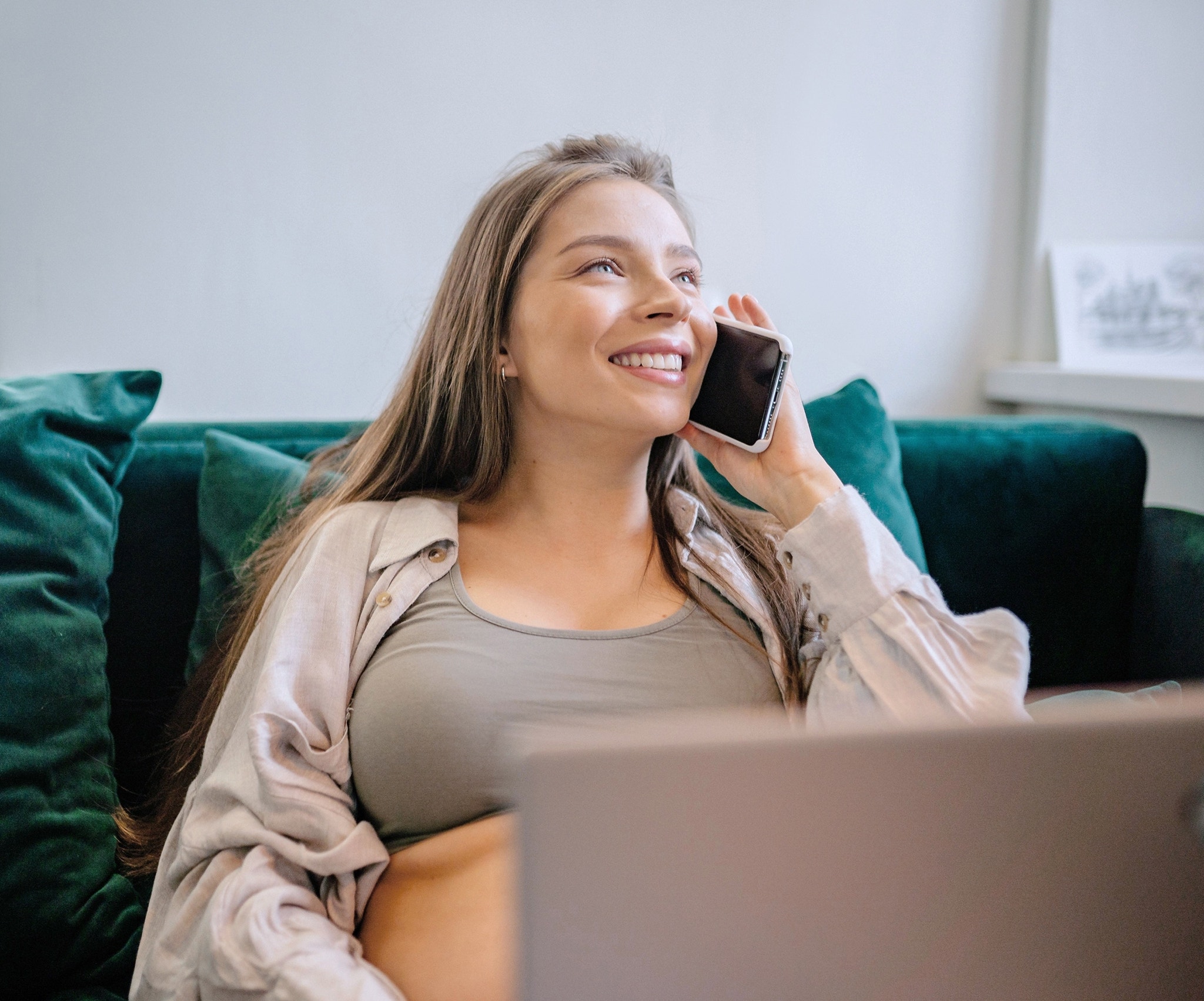 Young woman on the couch talking on smartphone