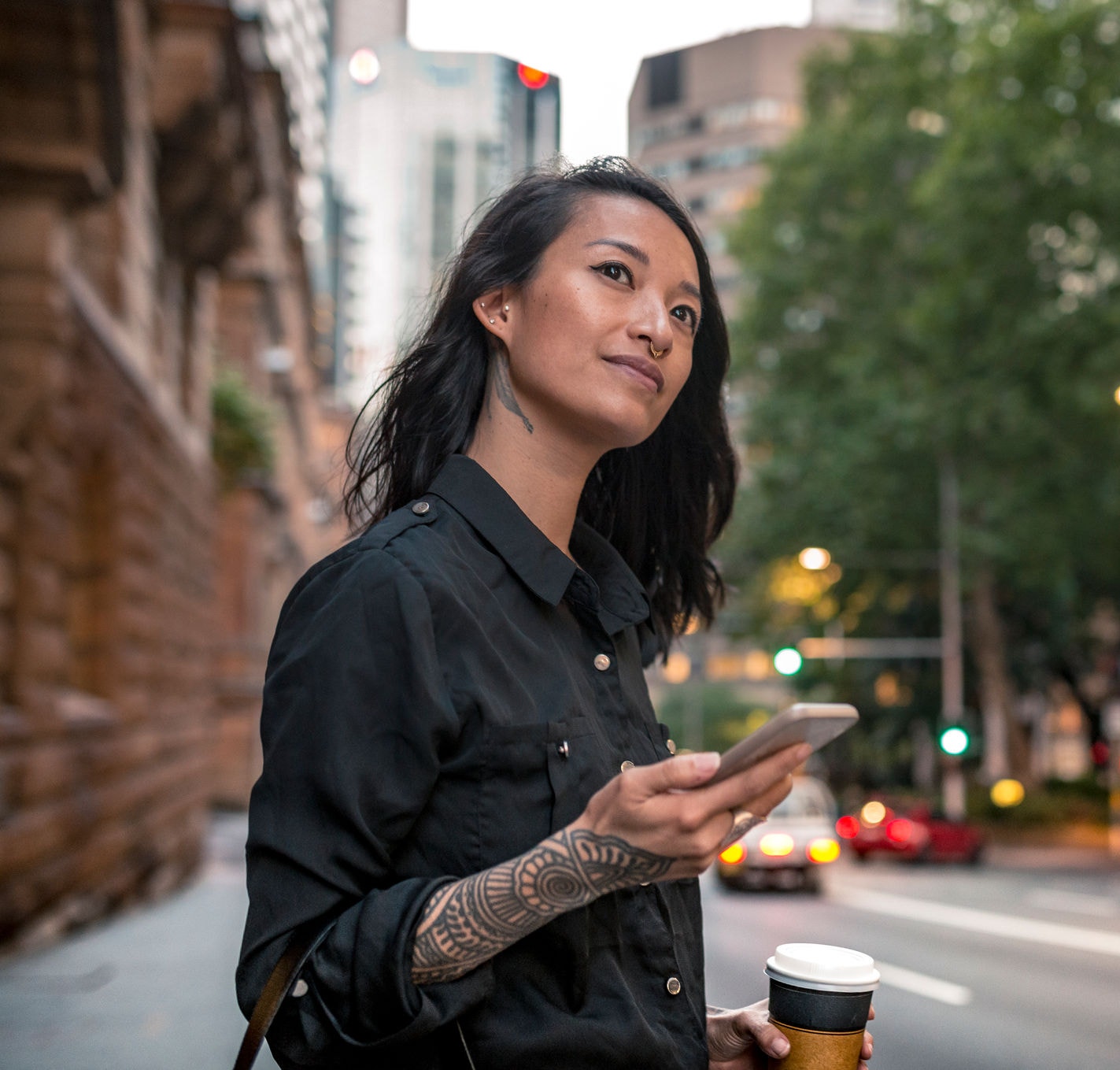 Young woman with a coffee on the street waiting for taxi