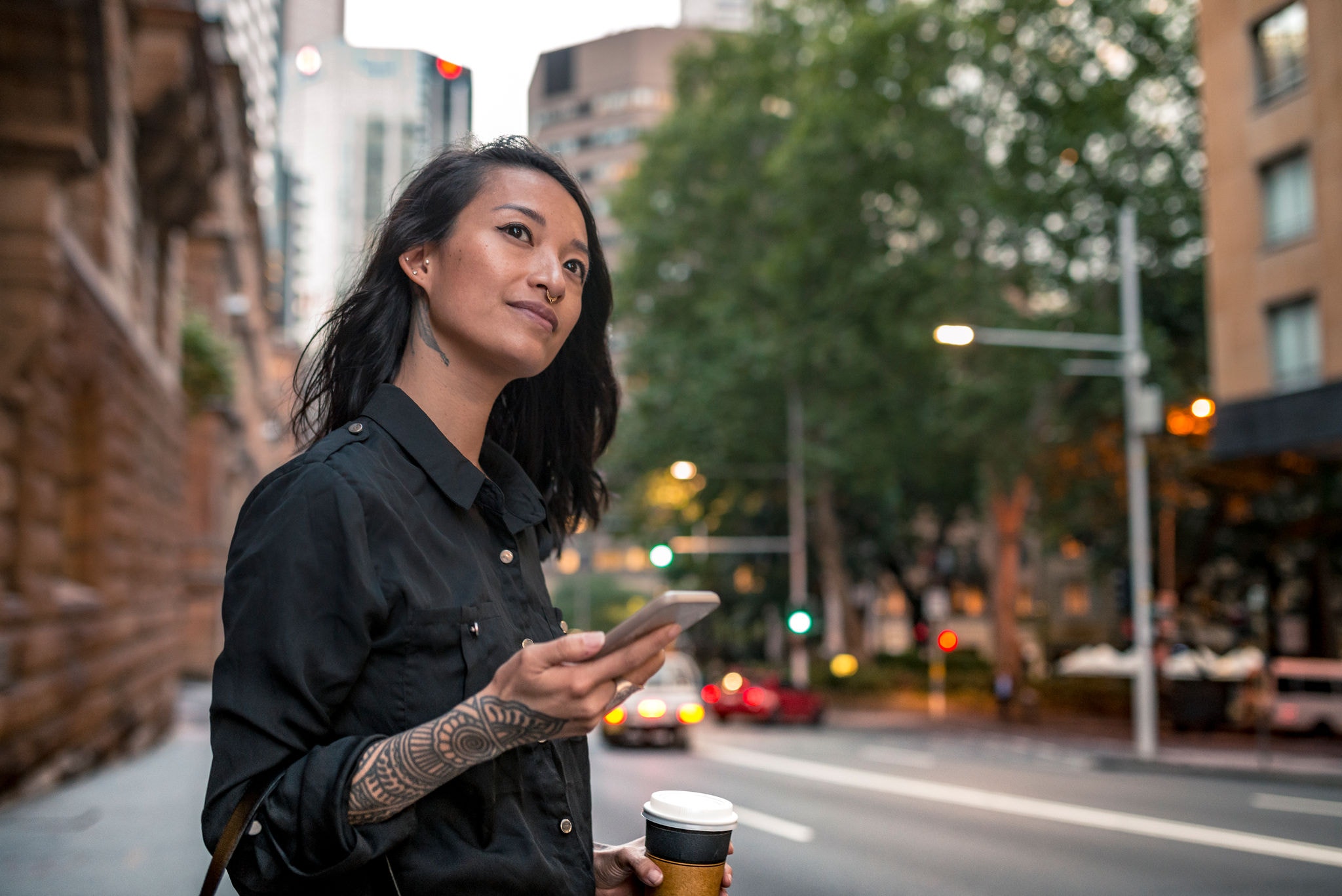 Young woman with a coffee on the street waiting for taxi