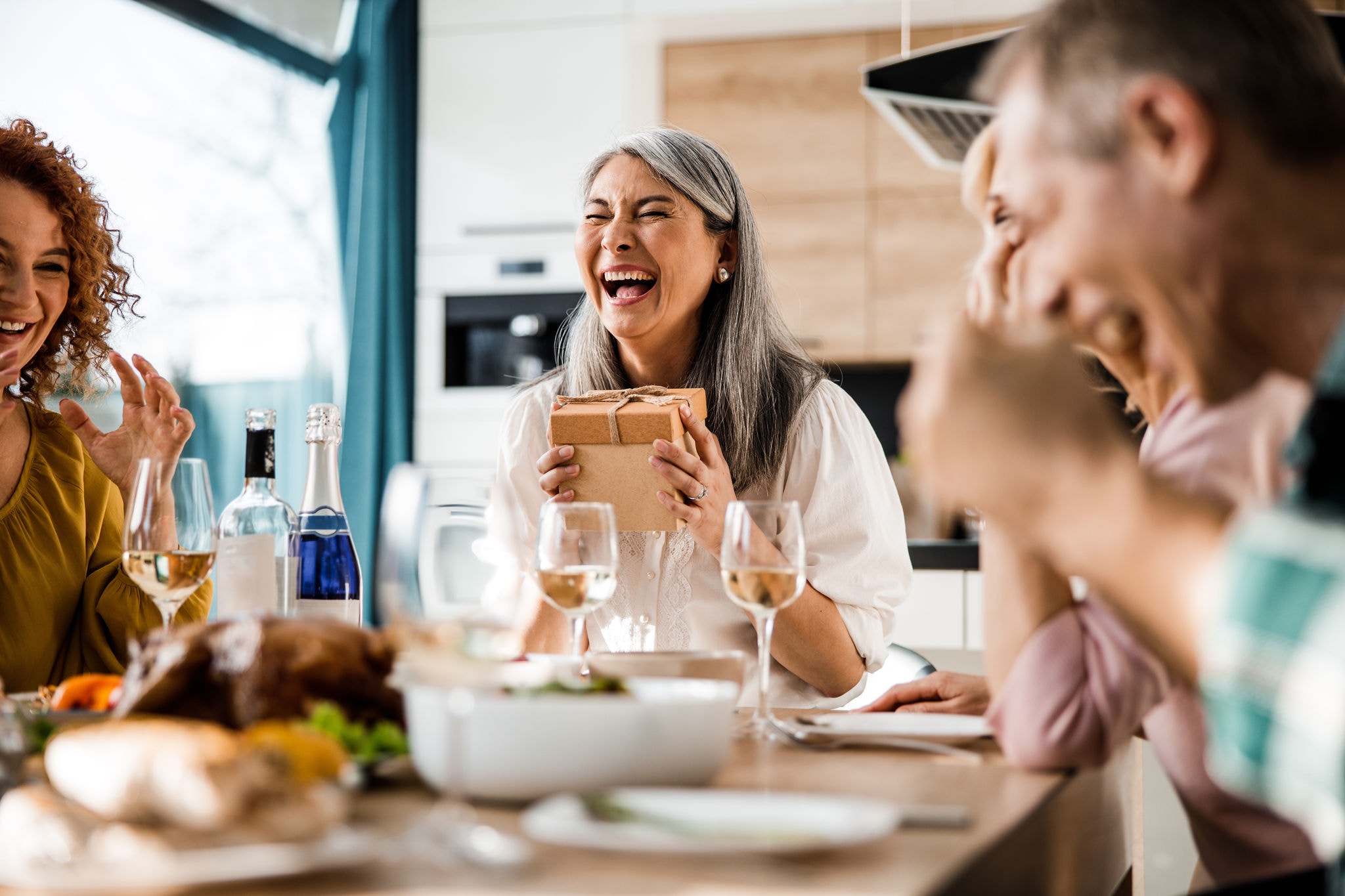 Group of friends laughing and enjoying a dinner at home