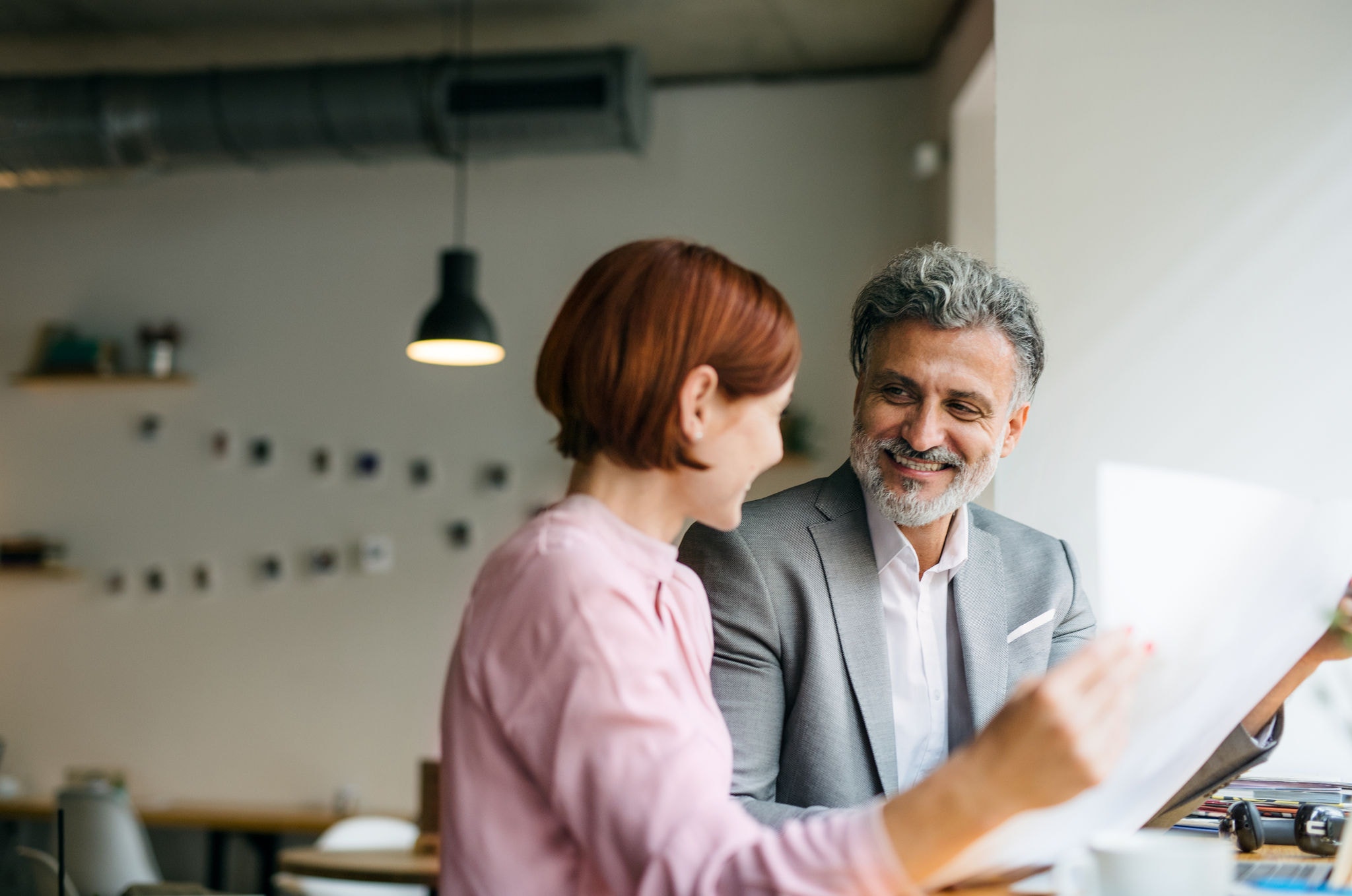 Man and woman having business meeting in a cafe, looking at blueprints