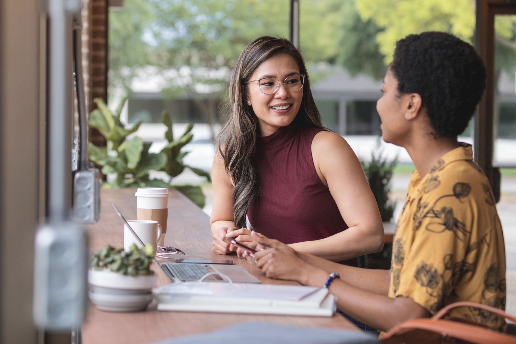 Canva-two-young-females-talking-working-coffee