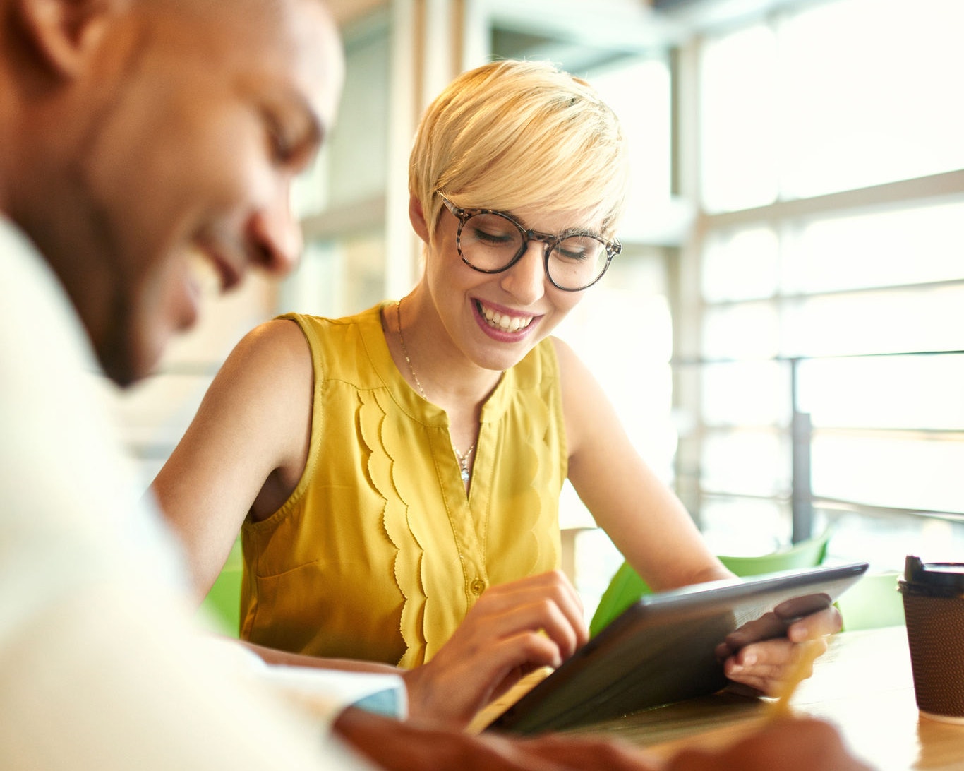 Team of young casual business people collaborating on an online project using a digital touchpad tablet computer in a bright modern office space. Serie with light flares