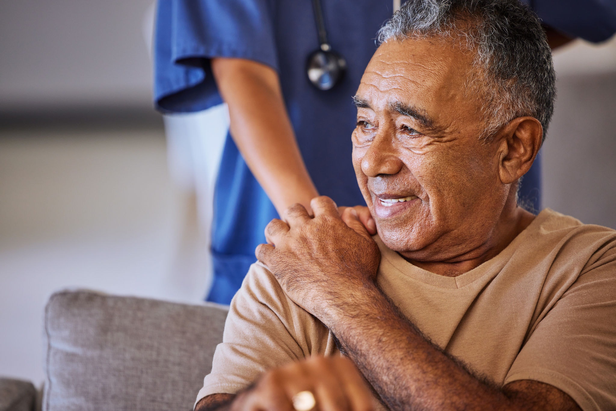 Nurse holds her elderly patient's hand, offering comfort during a checkup at the retirement home