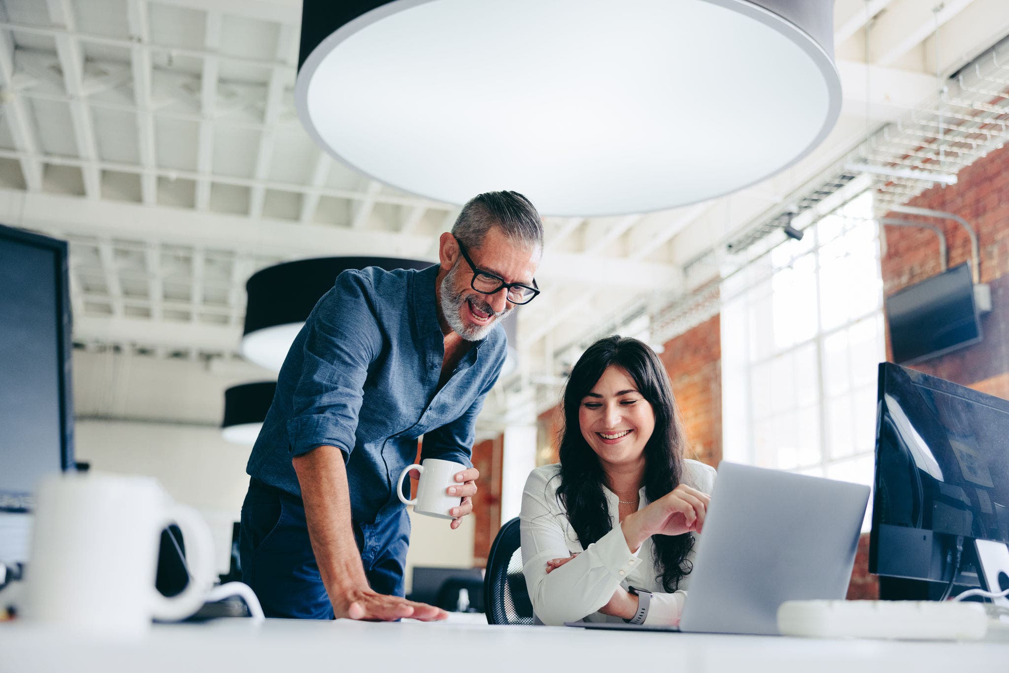 Creative businesspeople making success in the office. Happy mature businessman collaborating with his female colleague in a modern workplace. Two colleagues working on a project together.
