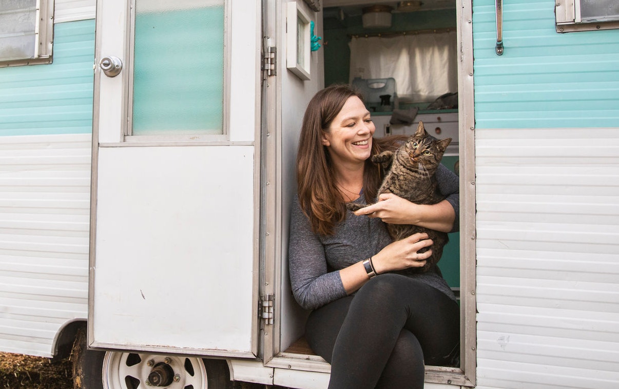 A young woman setting up camp in the wilderness with her trailer