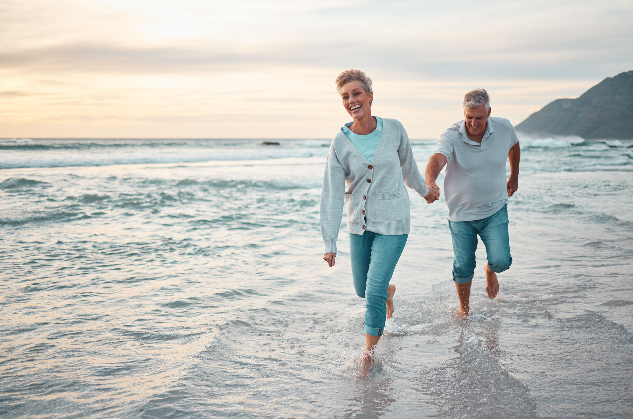 Couple walking in the water along the beach, enjoying retirement