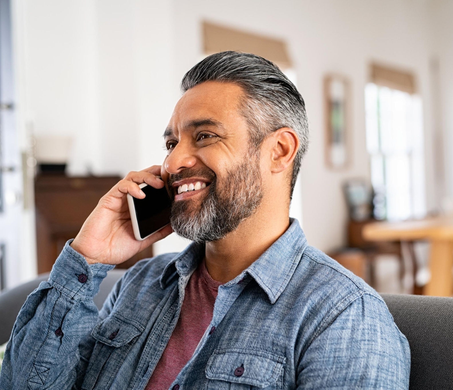 A man happily talking on the phone at home