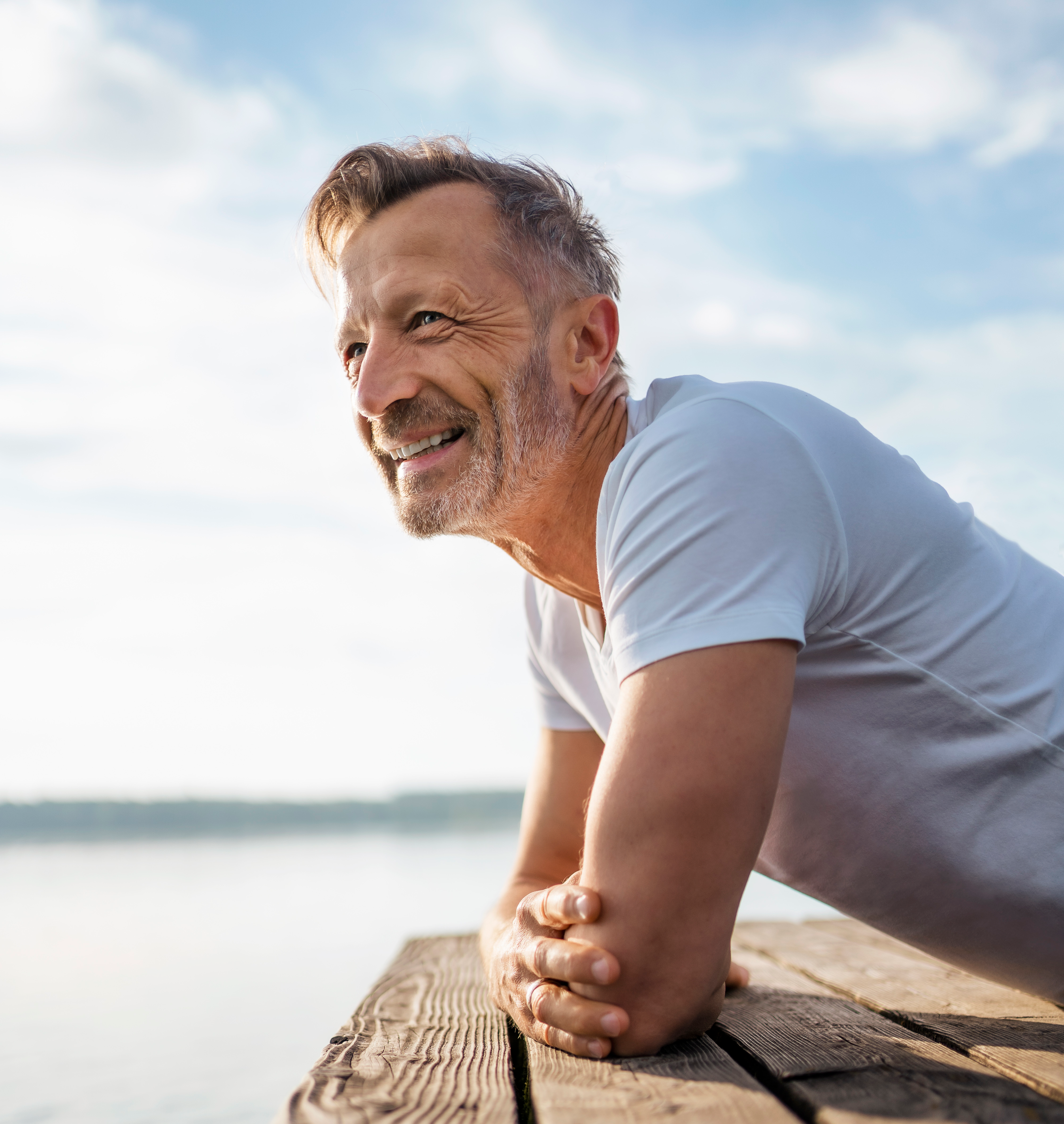 Man leaning on pier looking over water