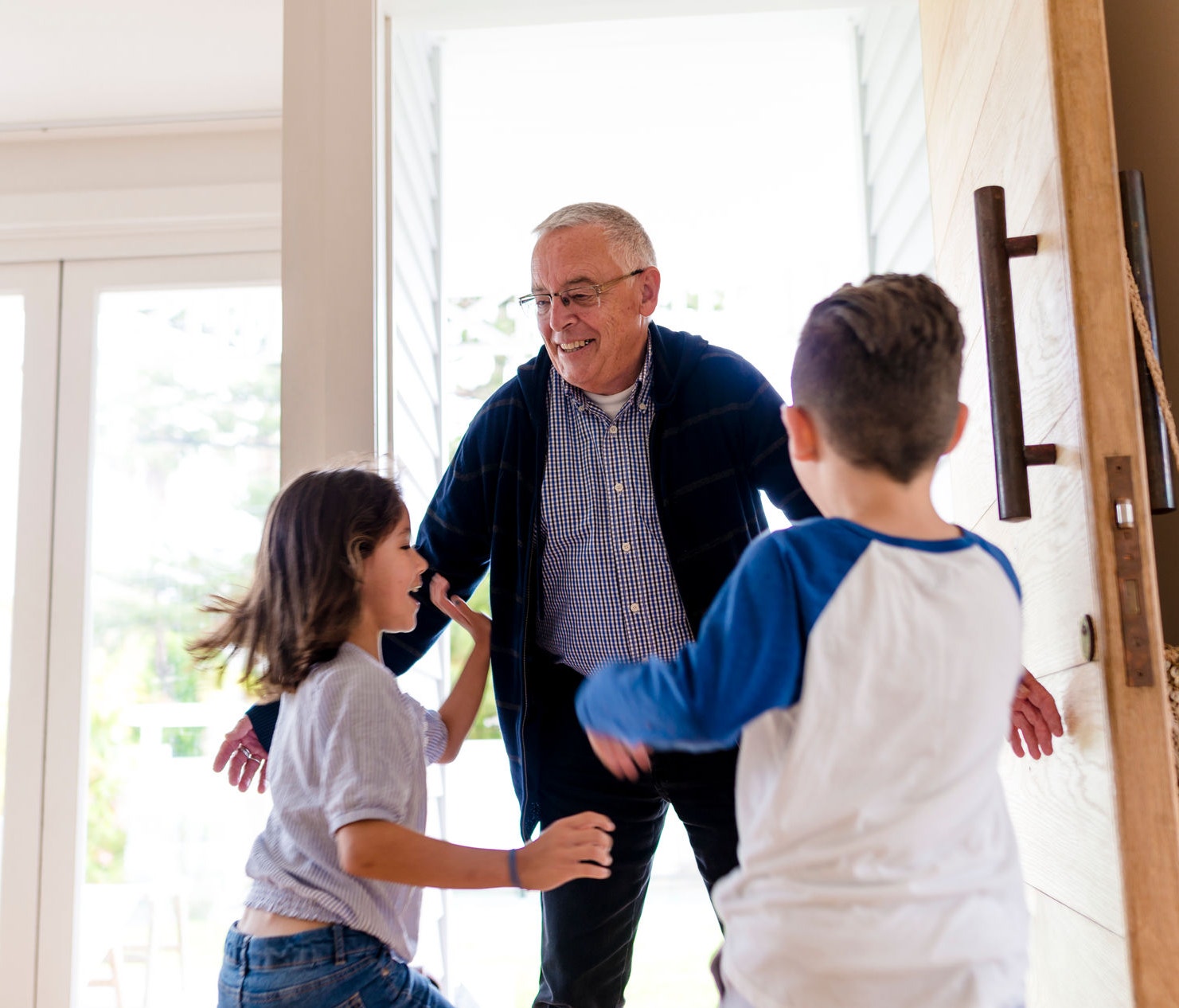 Happy grandfather arriving home and greeting his children with a hug and big smile.