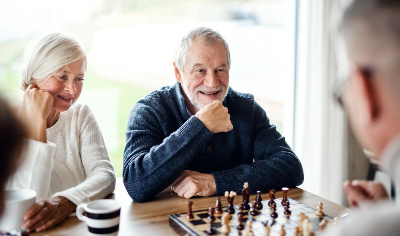Retired man at home playing chess with his family 