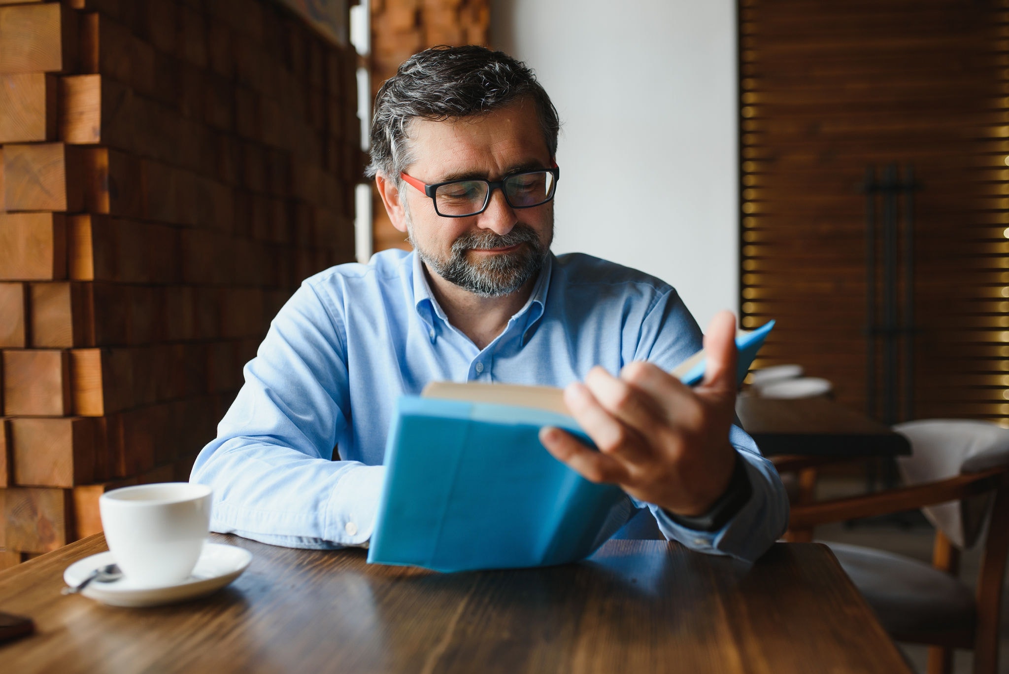 Man at home reading a book while enjoying a cup of coffee
