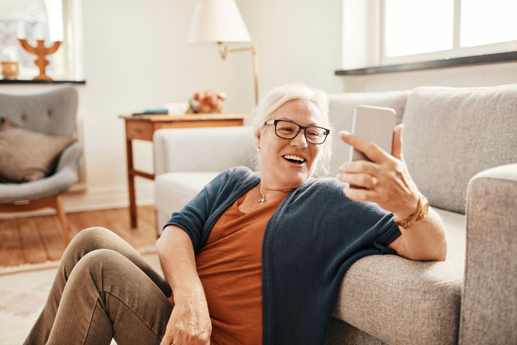 Close up of a senior woman using a phone in the living room