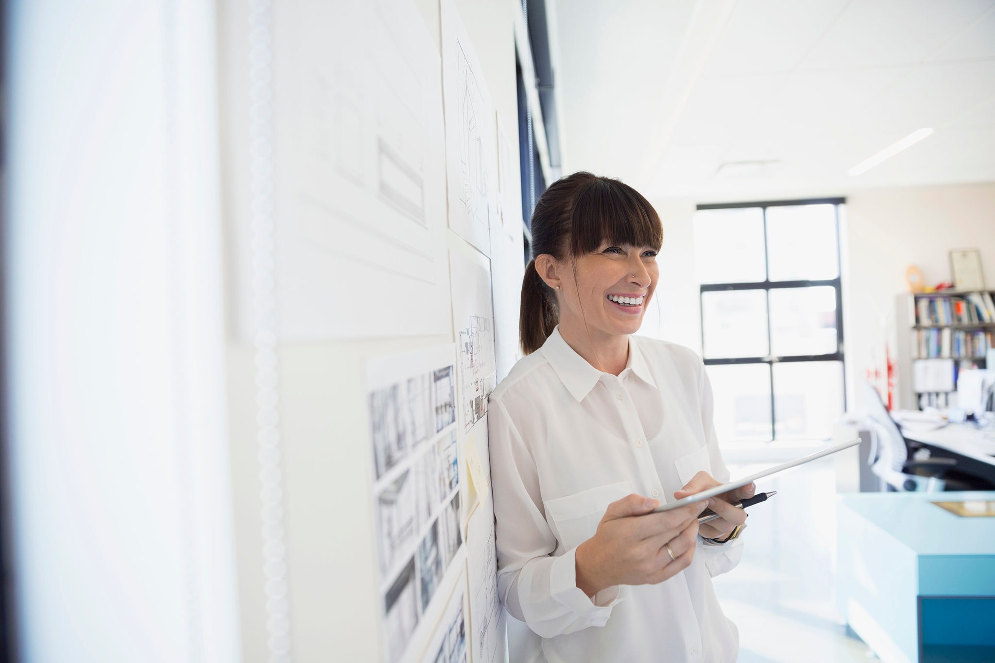 Woman smiling while leaning against the wall in a meeting room
