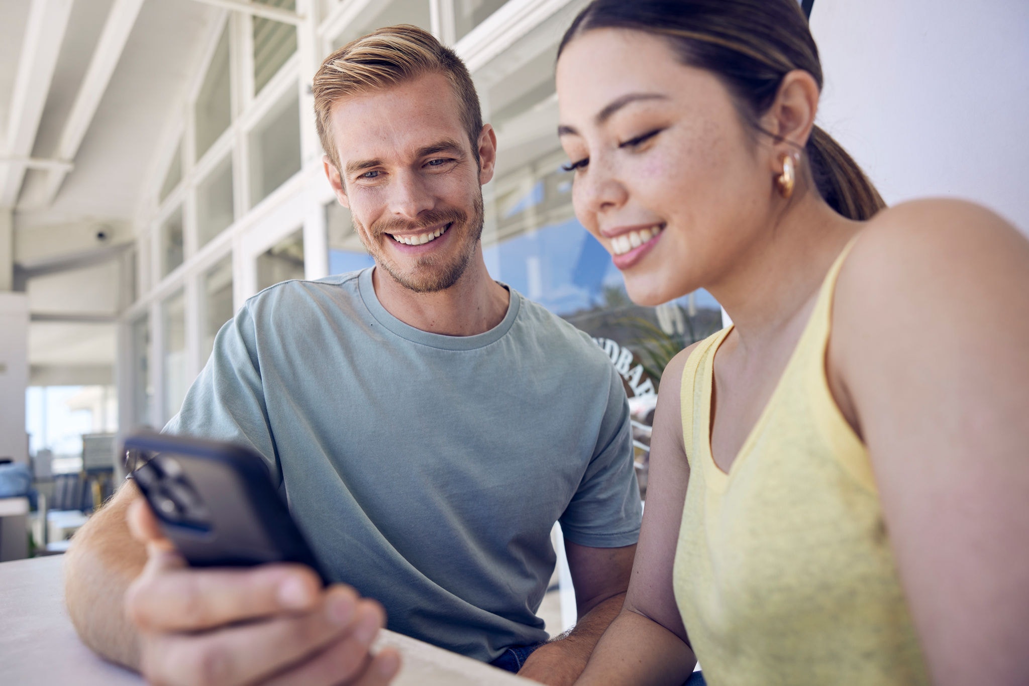 A man and woman sitting together looking at a phone.
