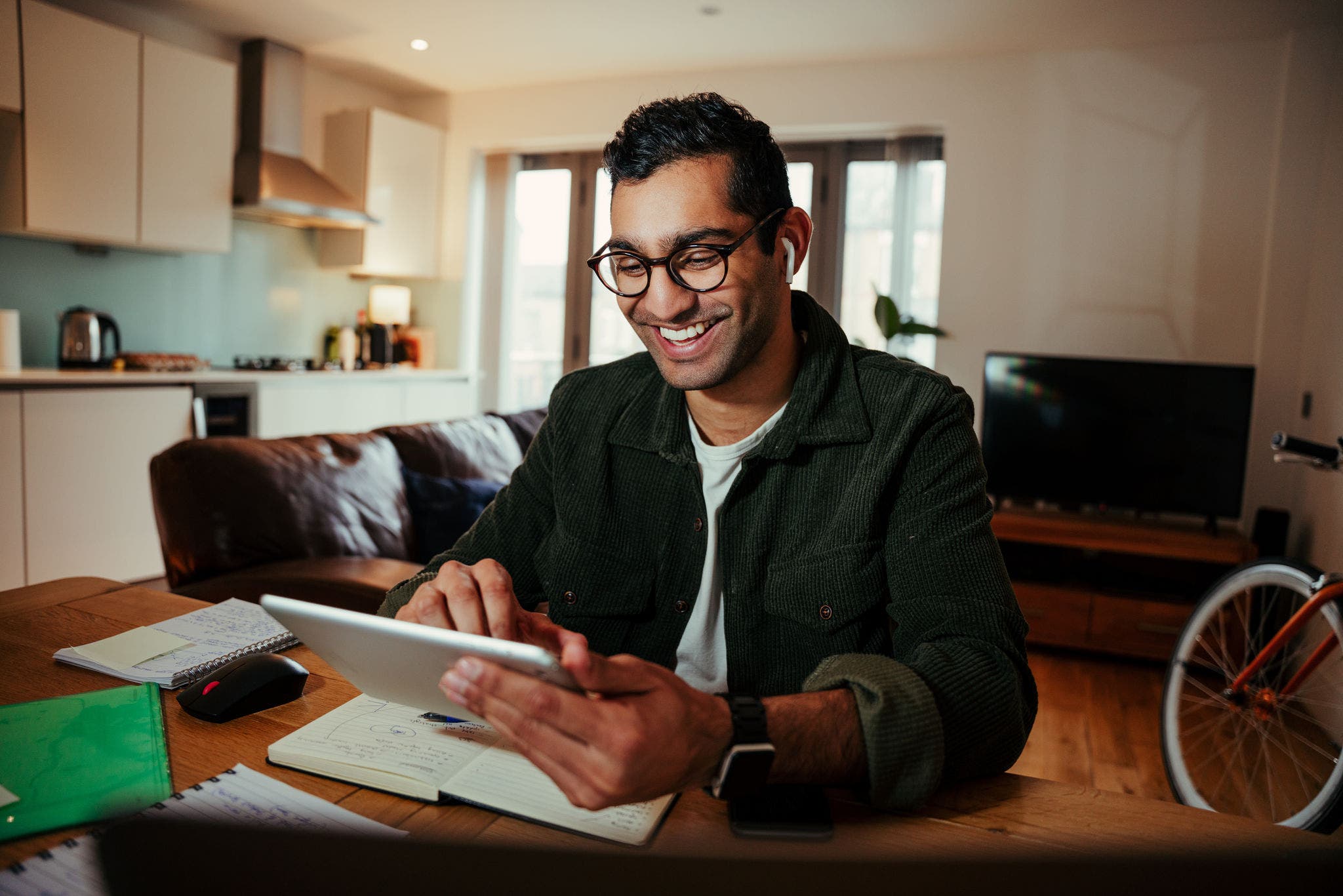 Young man face timing family from digital tablet at home