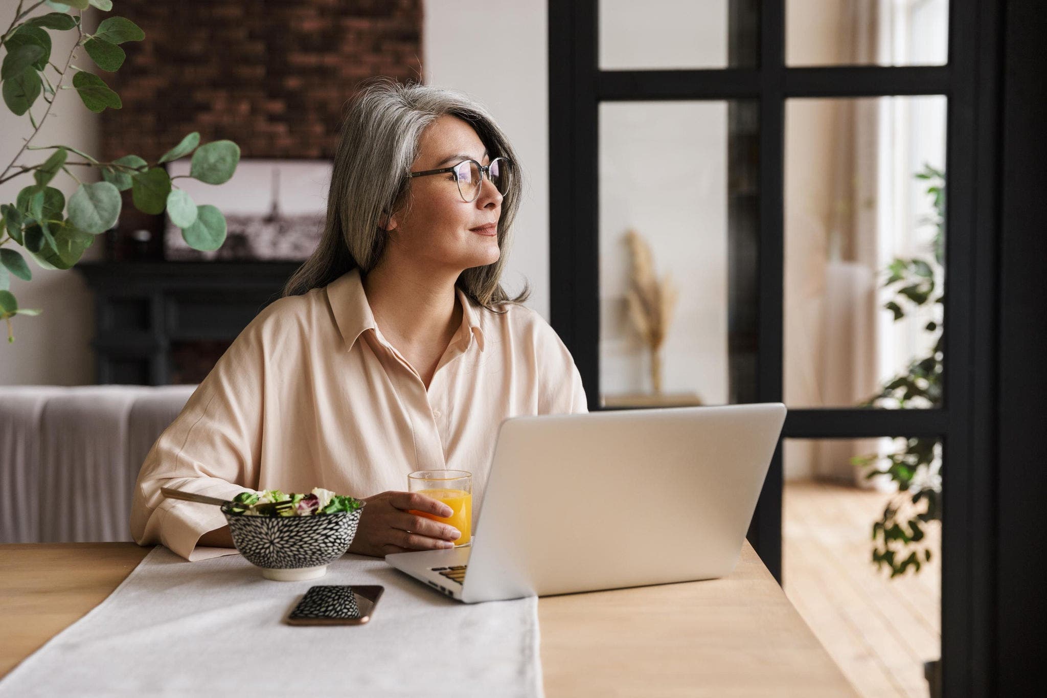 Woman working at home looking outside her window 