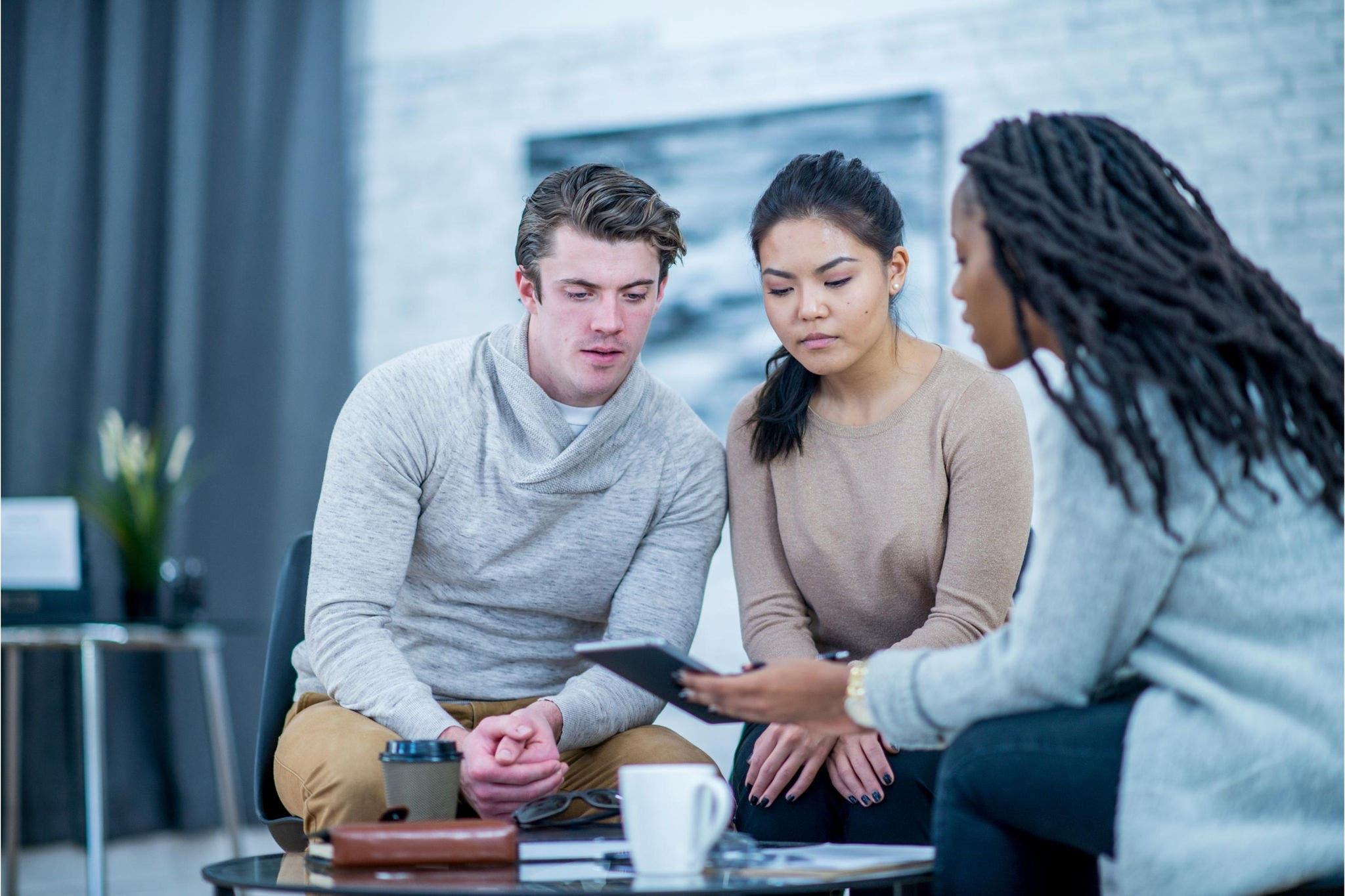 Female adviser meeting with couple, looking at a tablet