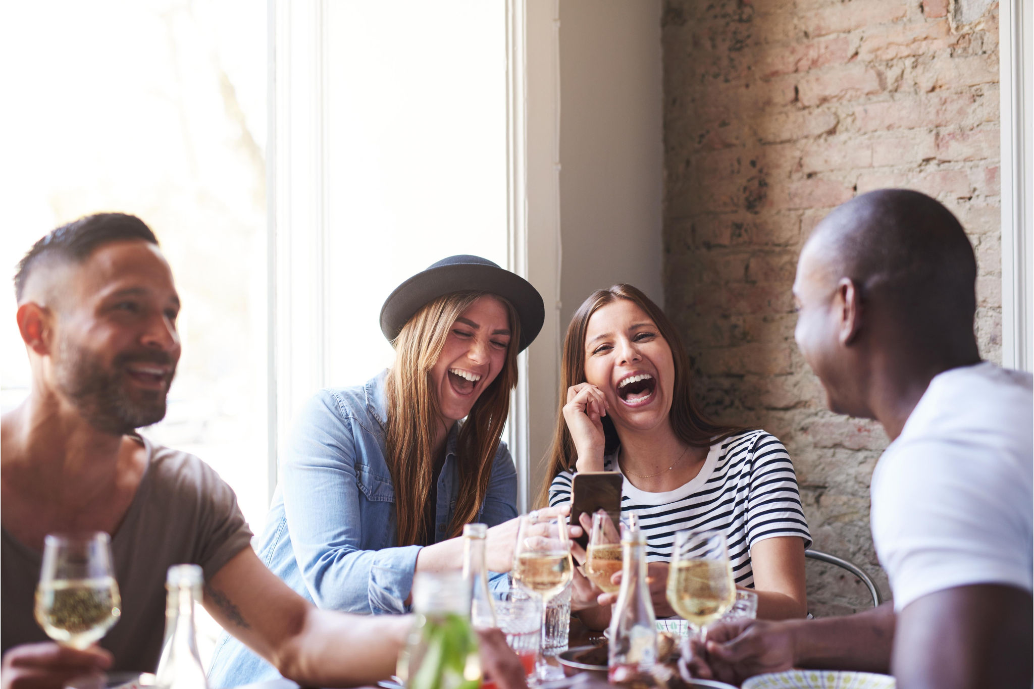 Friends sitting at a restaurant laughing while drinking wine