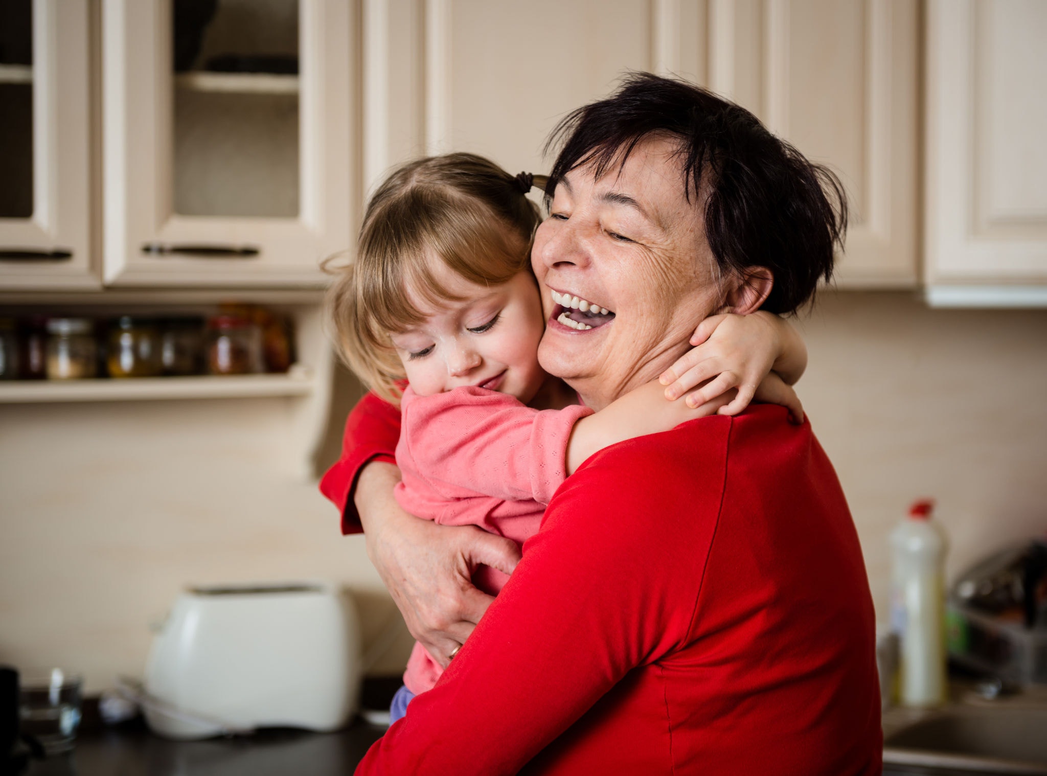 Woman hugging her granddaughter in kitchen 
