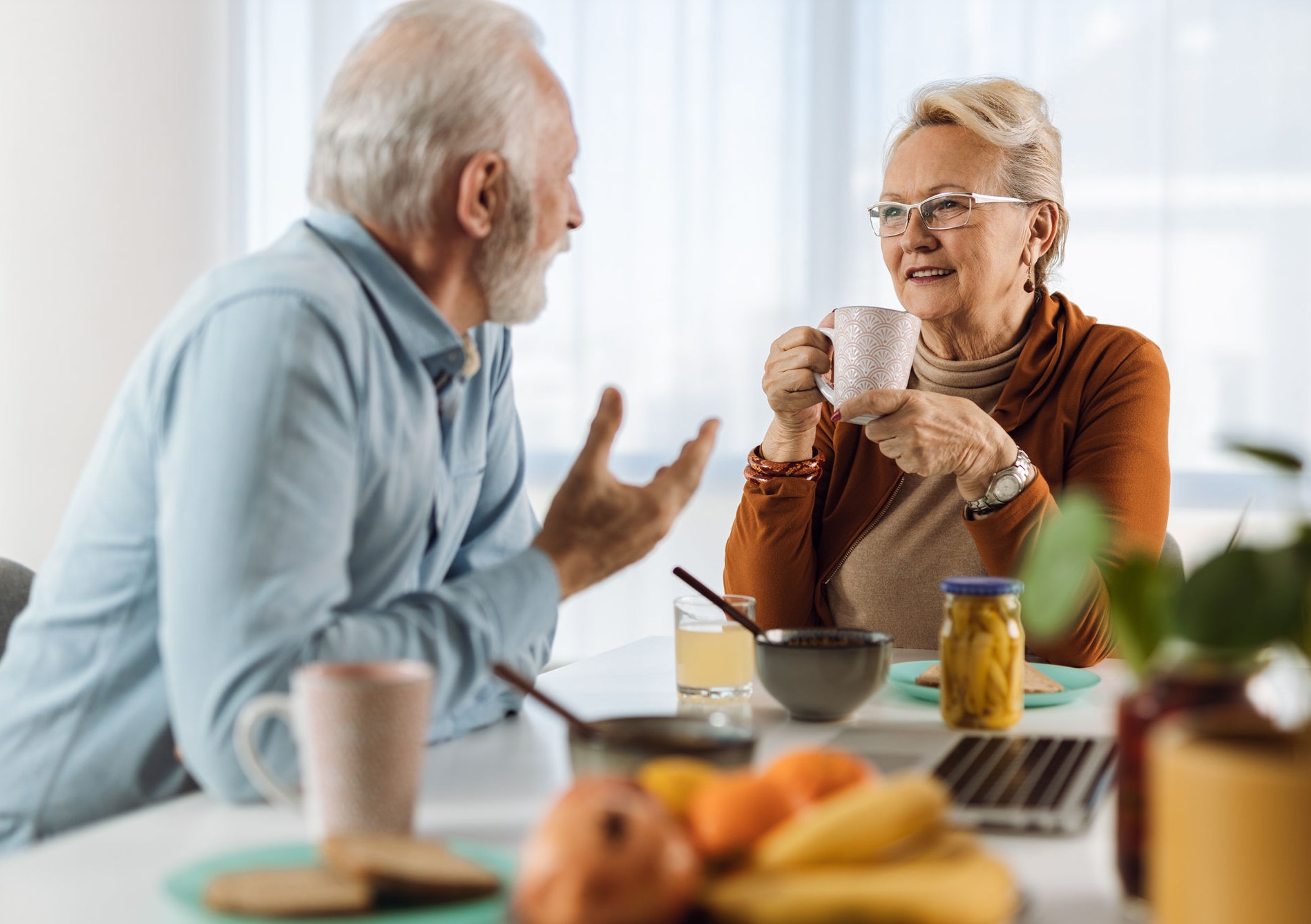 Retired couple talking to each other at dining table