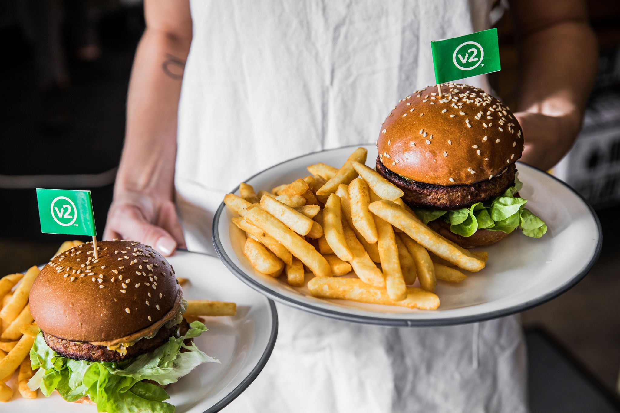 image of waiter holding two plates of burgers and chips