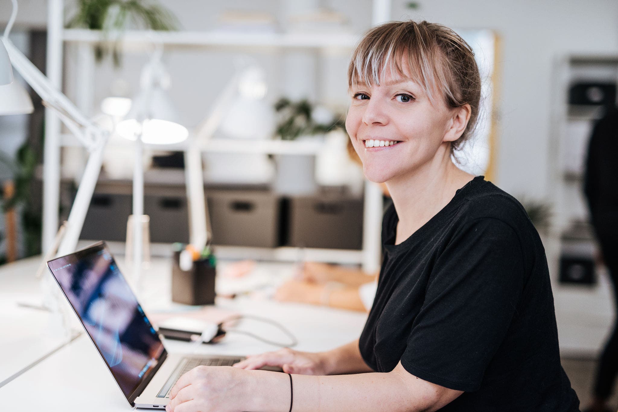 Woman working on her laptop and smiling at the camera