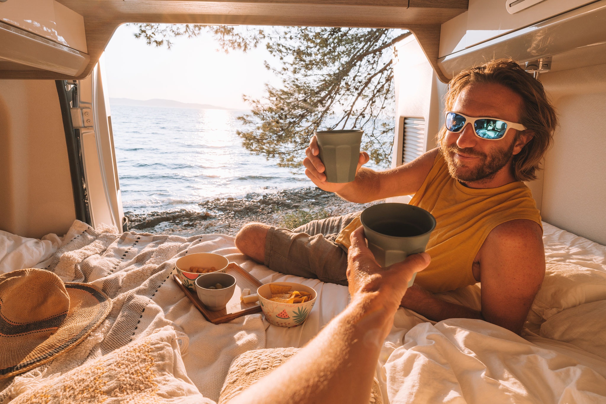 Couple living the van life experience watching stunning view while lying on the bed of the back of a camper