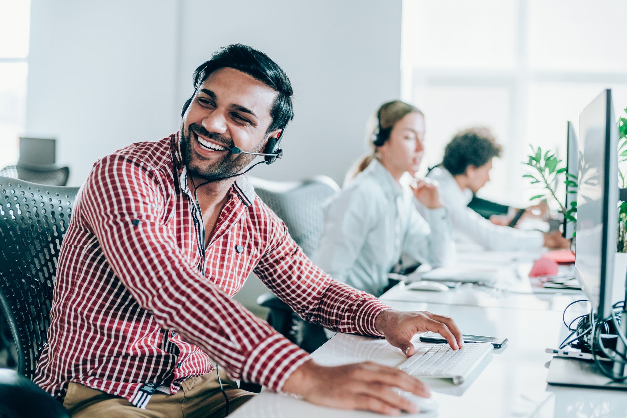 Cheerful young man working in a call center with his team
