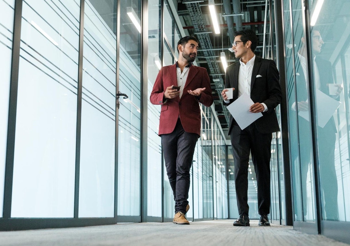 Two businessmen walking down a corridor in an office building