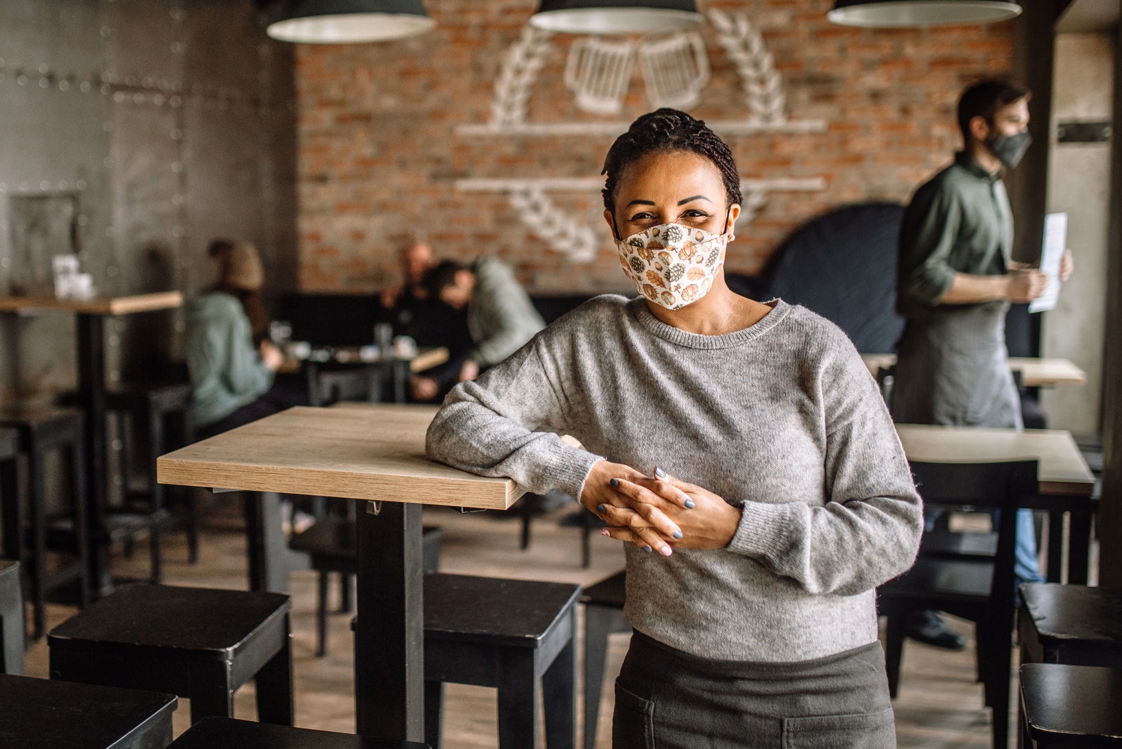 Confident female cafe owner leaning the table, standing in her reopened restaurant, waiting for a customers