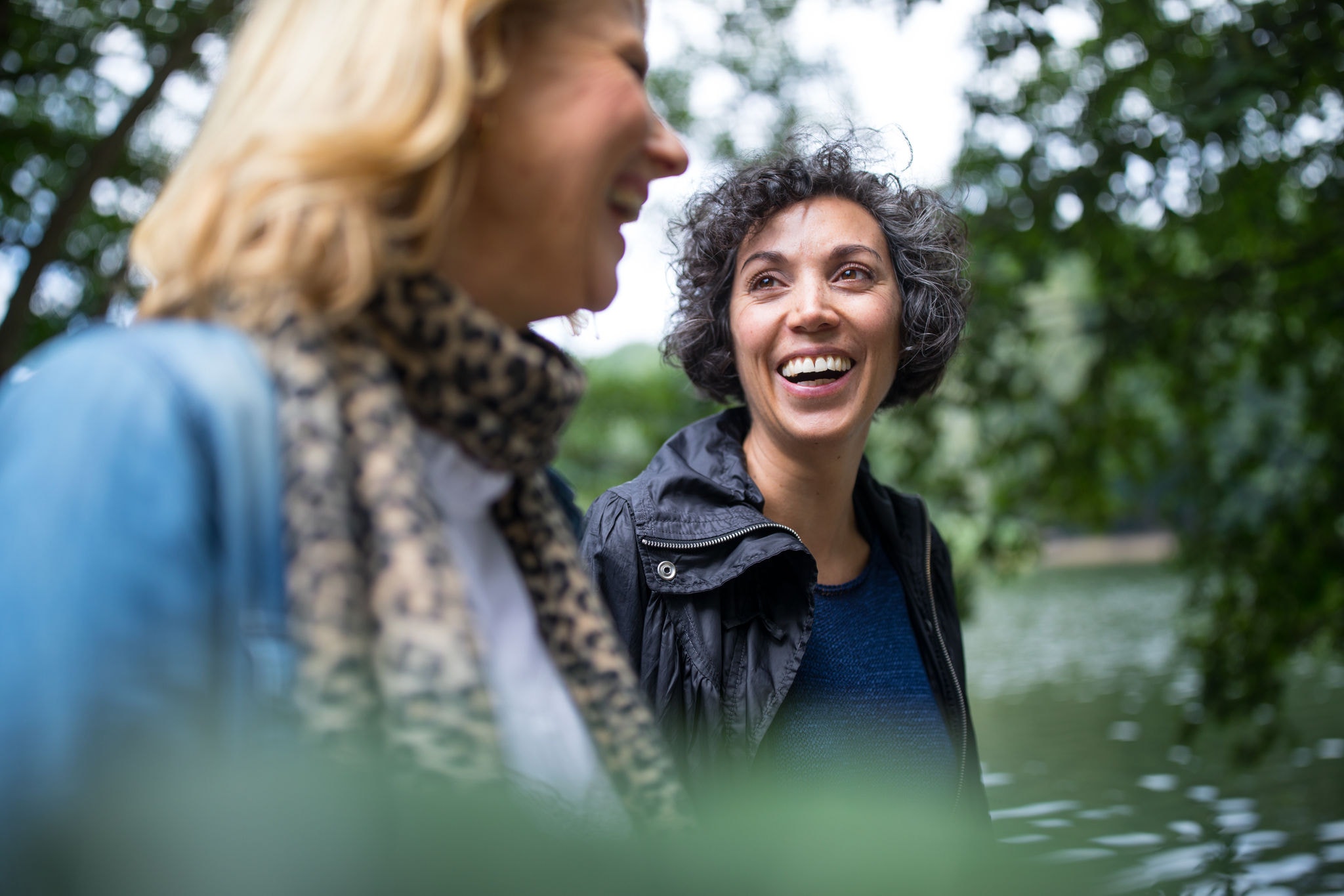 Female friends laughing and walking along the lake