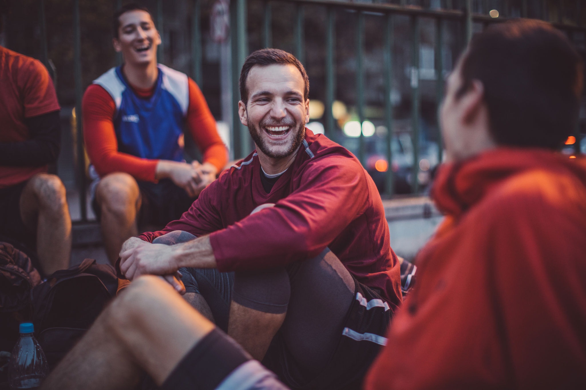 Young men playing basketball on courtyard at dusk. They gather on courtyard, preparing for game, play basketball, performing exhibitions and slam dunking