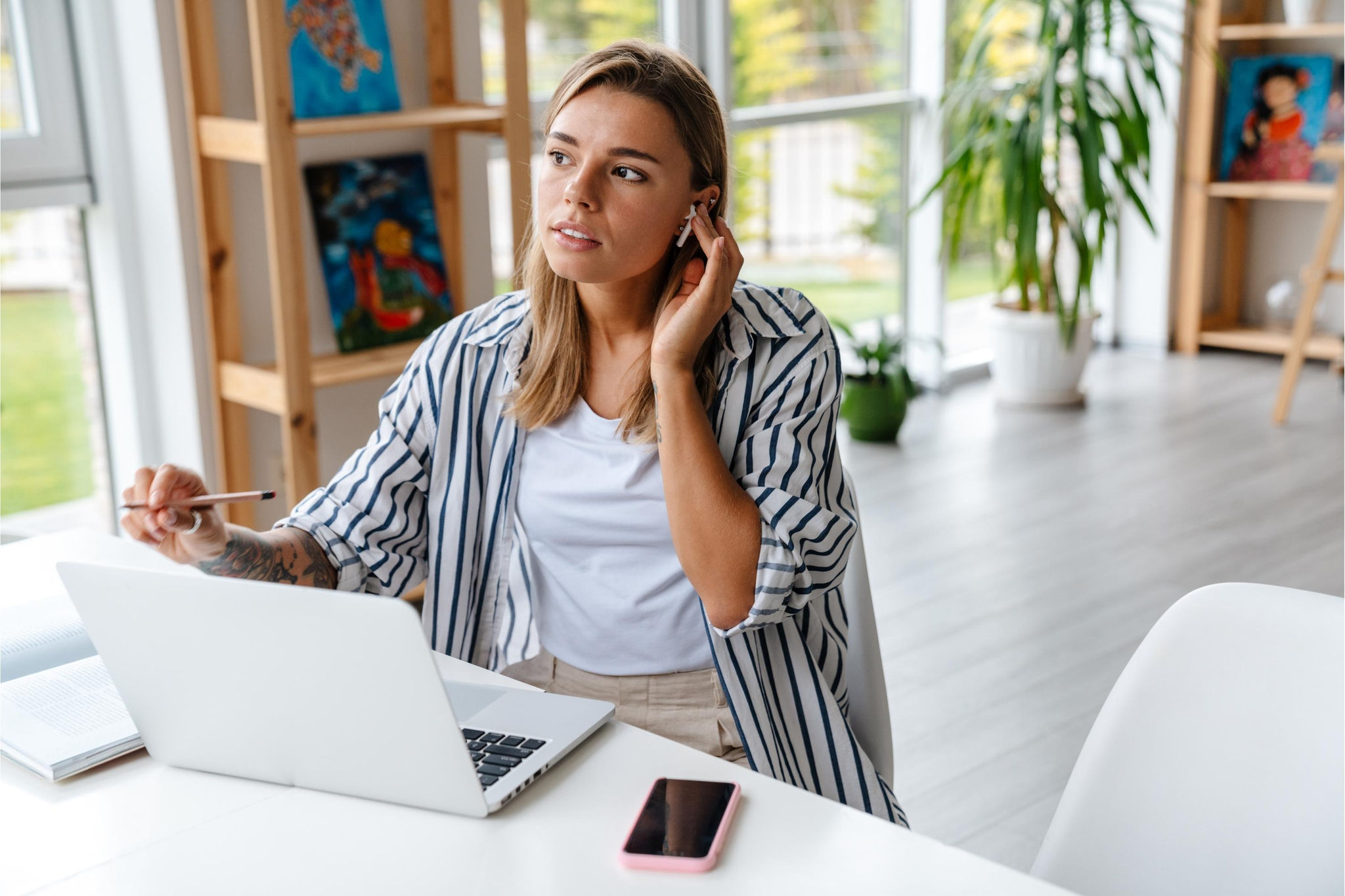 canva-young-woman-working-home-laptop-phone-earphones