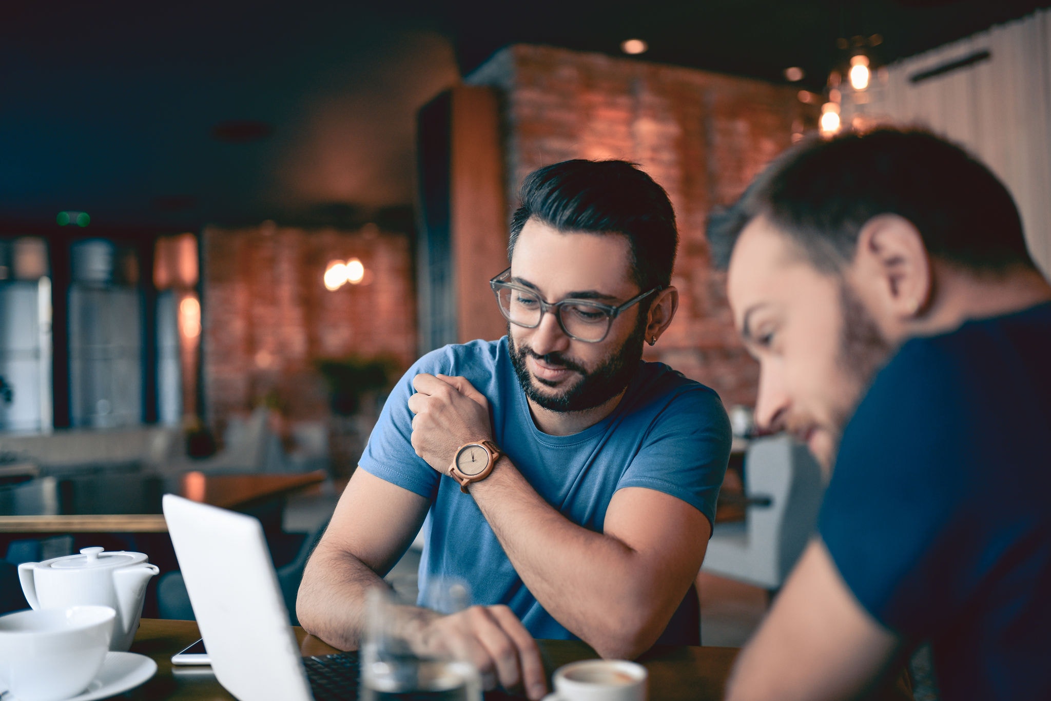 Male friends working on laptop in a cafe