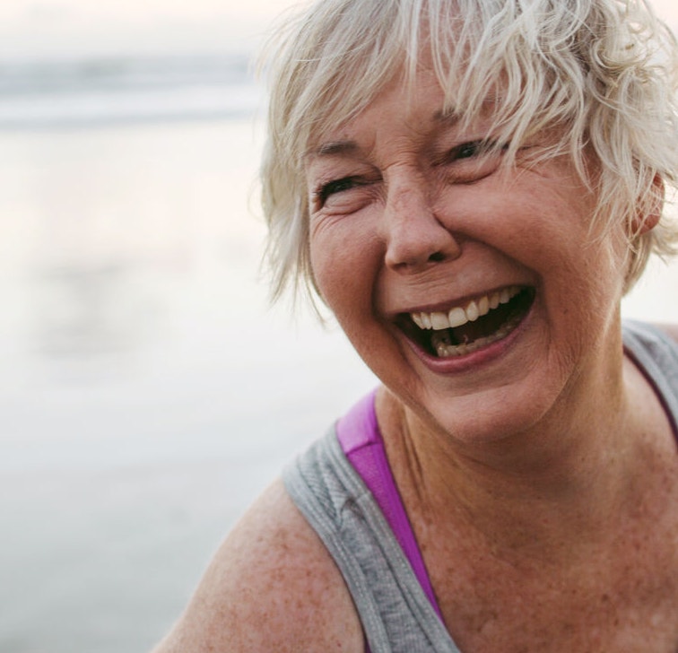 Vibrant mature woman enjoying herself on the beach at sunset