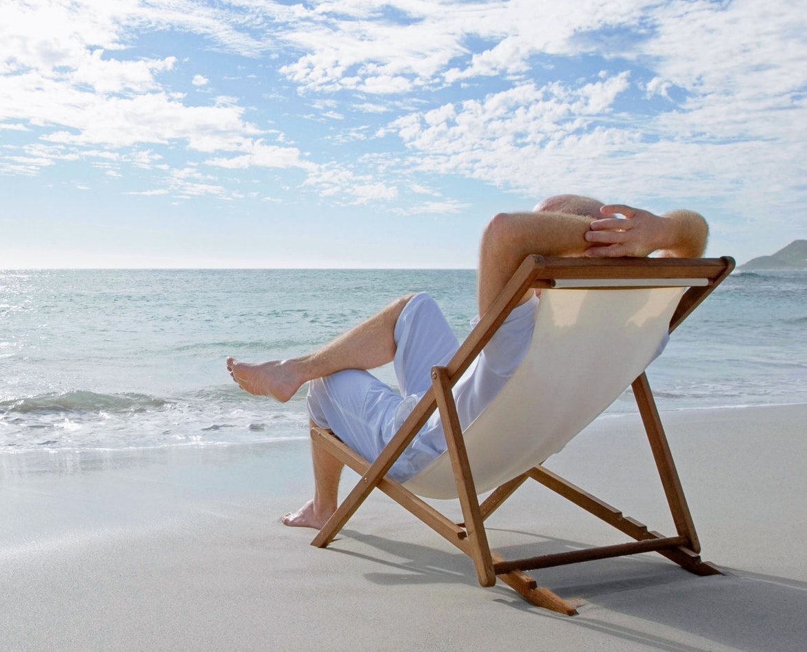 A man relaxing on a lounge chair at the beach