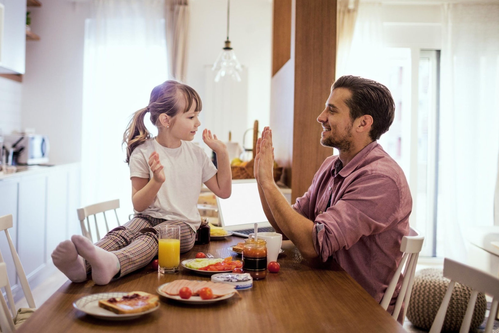 Father and daughter sitting in the dining room, eating and playing together