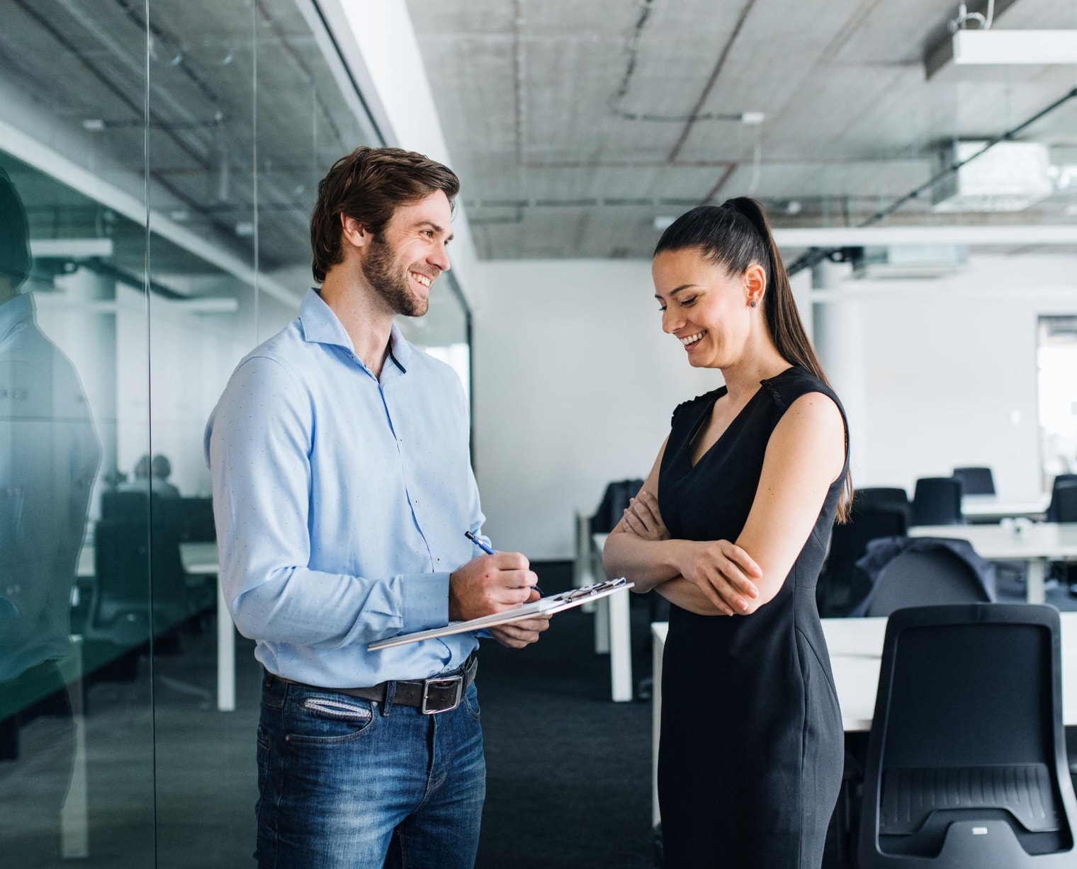 Co-workers standing in the office with a clipboard 