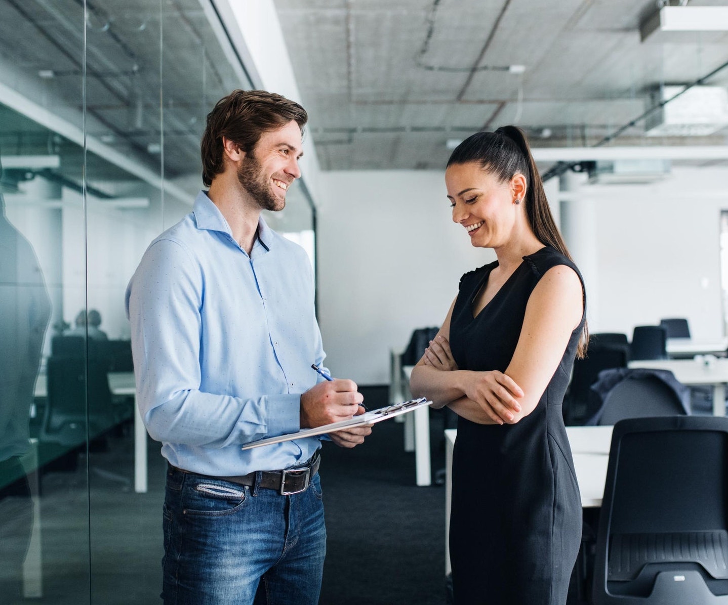 Co-workers standing in the office with a clipboard 